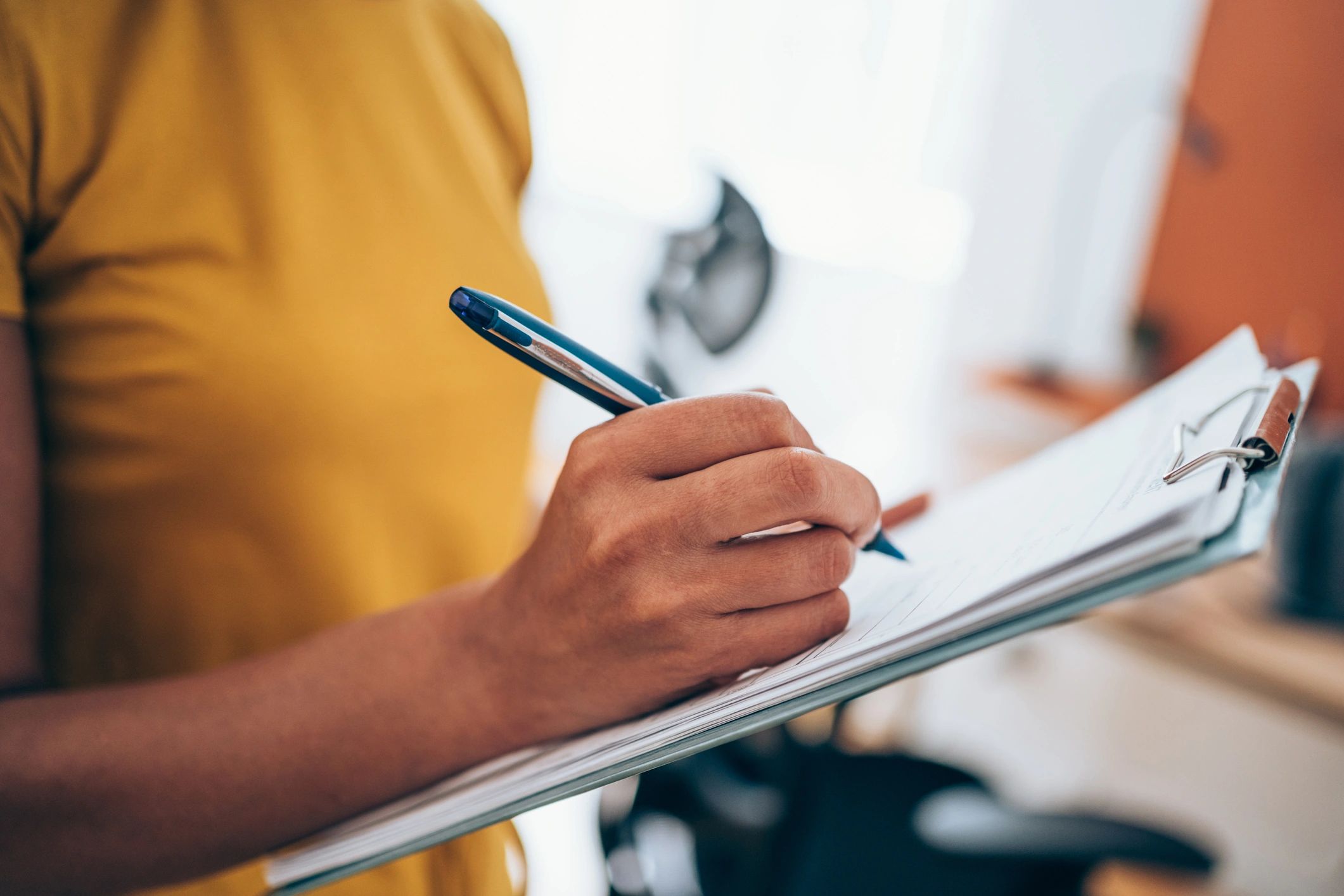 Business professional writing notes on a checklist clipboard
